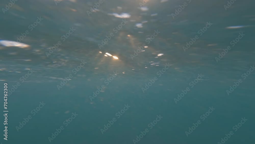 Under ocean water surface with orange sun light ray down.