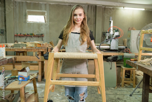 A female craftsman furniture designer makes a chair, marks various dimensions on a blueprint, and assembles a wooden one. Carpenter working in the studio