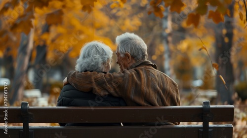 Elderly Couple Embracing on Autumn Bench. Senior couple seated closely, enjoying an autumn day.