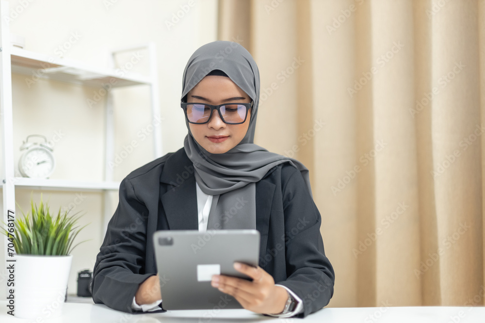 Young muslim beautiful businesswoman wear hijab using tablet business thinking about work in workplace. Young muslim beautiful businesswoman wear hijab using tablet business thinking about work in workplace.