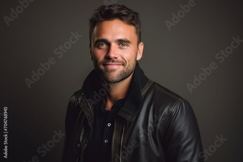 Portrait of a handsome young man in leather jacket on dark background © Inigo