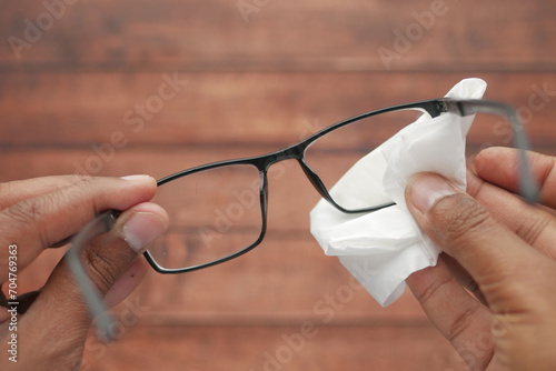cleaning eyeglass with tissue close up 