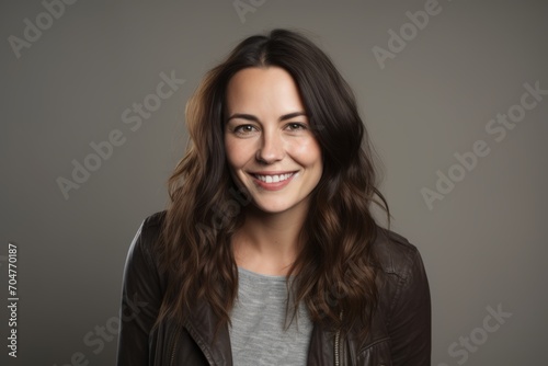 Portrait of a happy young woman in leather jacket on grey background