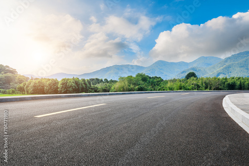 Asphalt highway road and green forest with mountain natural landscape under blue sky © ABCDstock