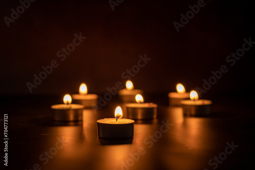 Many candles lit against a black background.Burning candles on dark tableMemory 