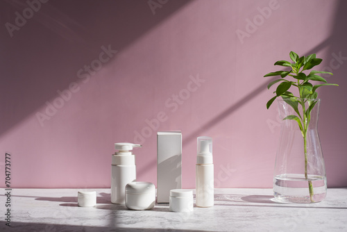 The set of cosmetic packaging with natural leaf on pink background. For clean beauty and skin care concept.
