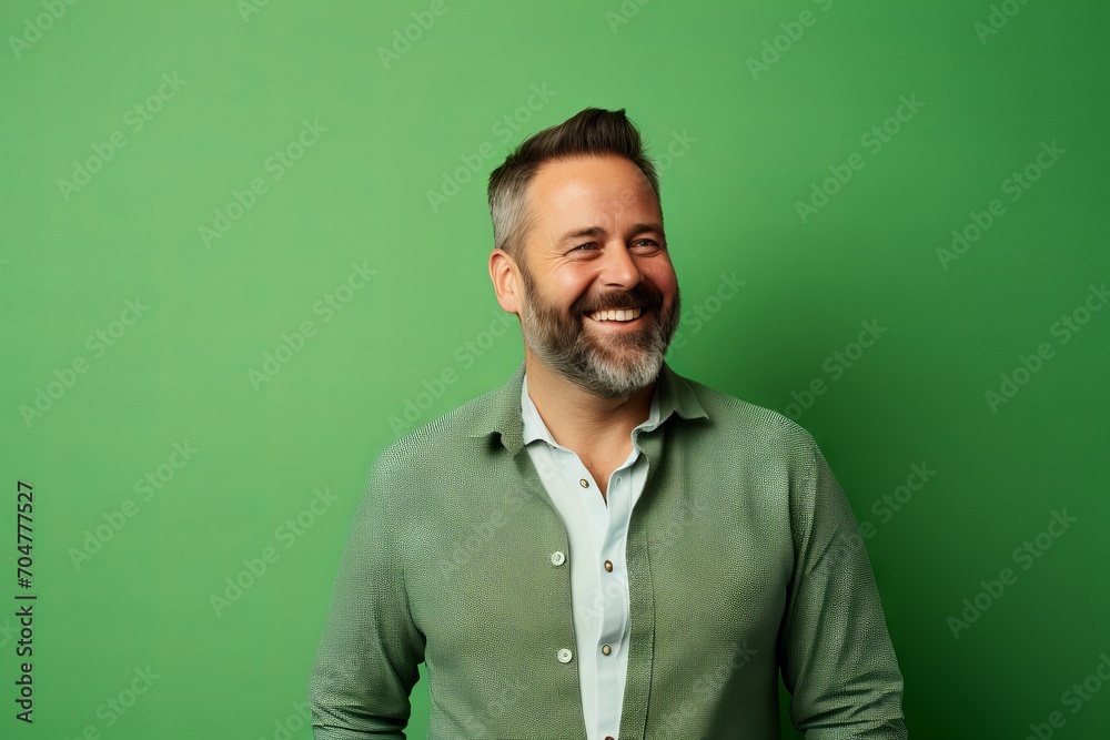 Portrait of a happy mature man laughing against a green background.