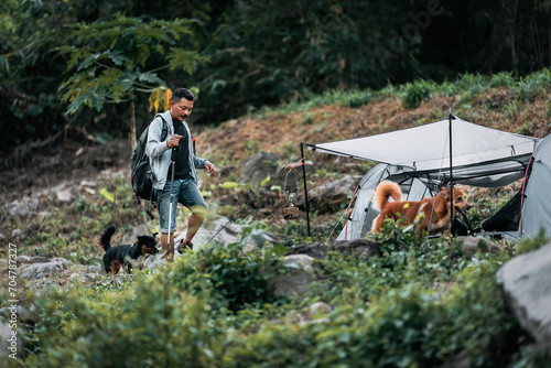 Hikers walk on rocks with dog in the stream flowing from the waterfall bact to his tent in hill. photo
