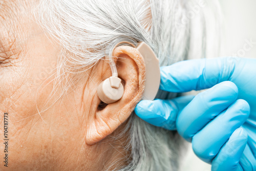 Asian senior woman patient wearing a hearing aid for treating hearing loss problem. photo