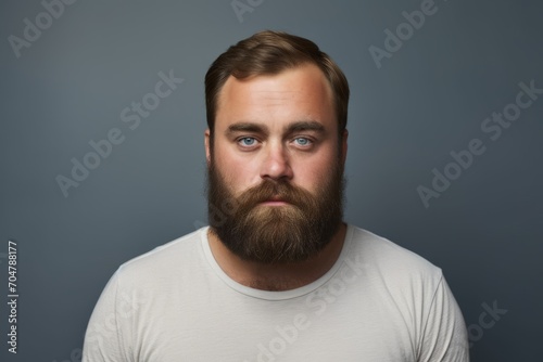Portrait of a handsome young man with beard and mustache on grey background