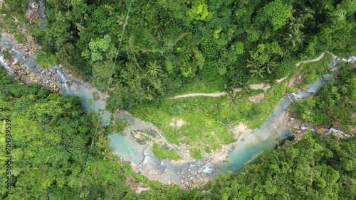 People trekking trail along creek in lush green jungle, Cebu. Aerial photo