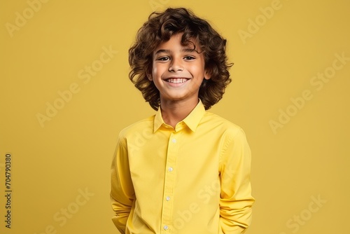 Portrait of a cute little boy with curly hair over yellow background