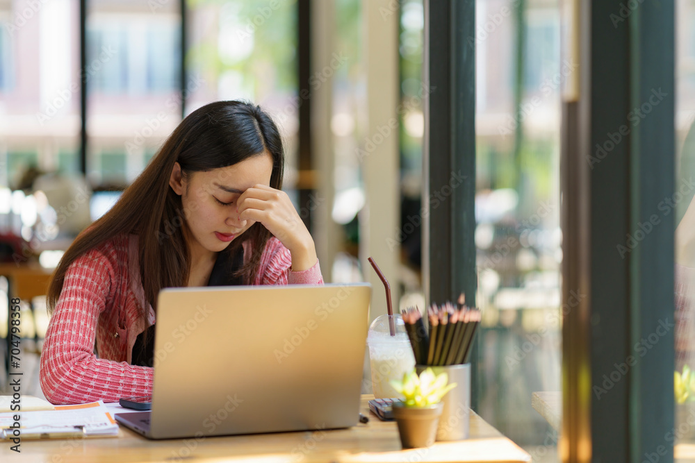 Asian businesswoman working on a laptop computer, stressed has a headache, and thinks hard from work at the office. Asian businesswoman working on a laptop computer, stressed has a headache, and thinks hard from work at the office.