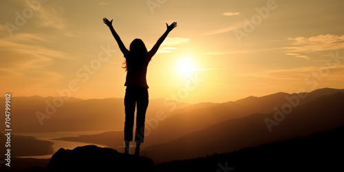 A woman stands atop a mountain at sunset, her arms raised in a triumphant gesture.