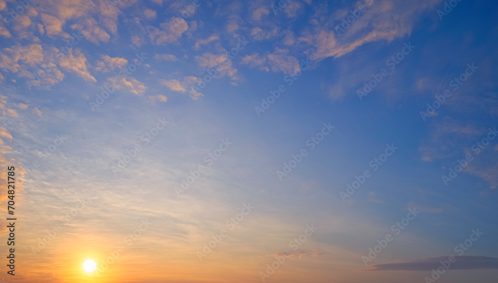 Sunset sky background in the evening with beautiful yellow sunlight and orange fluffy cloud on blue dusk sky Sunset sky background in the evening with beautiful yellow sunlight and orange fluffy cloud on blue dusk sky
