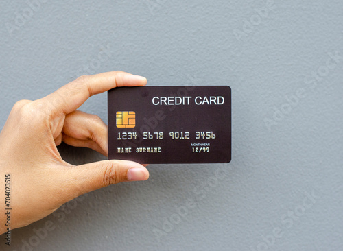 female hand holding a black credit card mockup with security chip embedded on a gray background photo