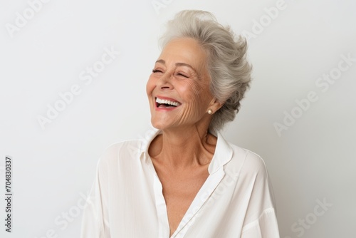 Portrait of happy senior woman laughing and looking at camera isolated over white background