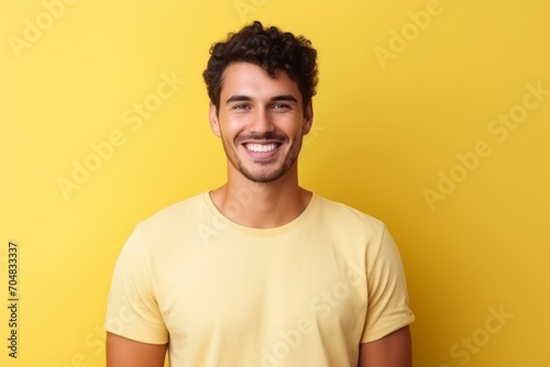 Portrait of a handsome young man smiling and looking at camera over yellow background