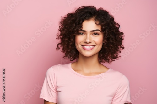 Portrait of a beautiful young brunette woman with curly hairstyle, isolated over pink background