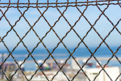 Close-up of a metallic fence on a blue background.