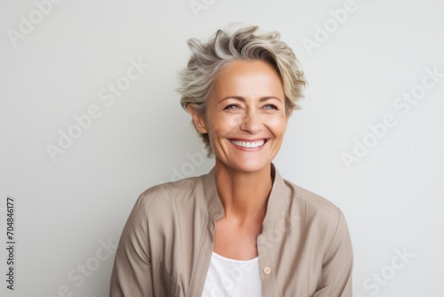 Portrait of a happy senior woman smiling at camera against grey background