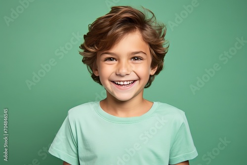 Portrait of a smiling little boy in a green t-shirt on a green background © Inigo