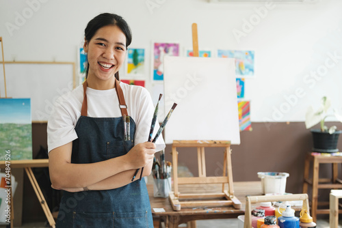 Young Asian female artist in art studio look at camera and smiling.