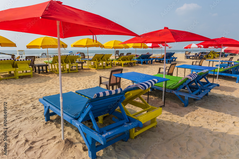 colorful wooden beach umbrellas and sunbeds loungers on sandy beach of ocean