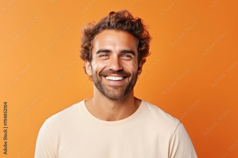 Portrait of a handsome young man with curly hair smiling against orange background Portrait of a handsome young man with curly hair smiling against orange background