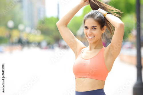 Happy sportswoman making ponytail in the street