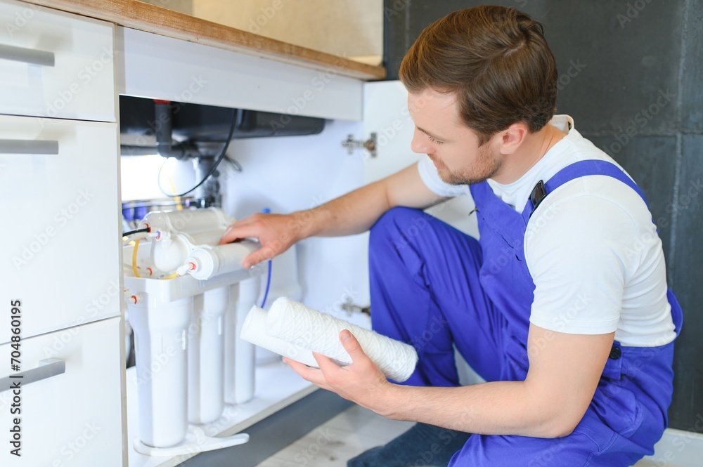Plumber installs or change water filter. Replacement aqua filter. Repairman installing water filter cartridges in a kitchen. Installation of reverse osmosis water purification system.