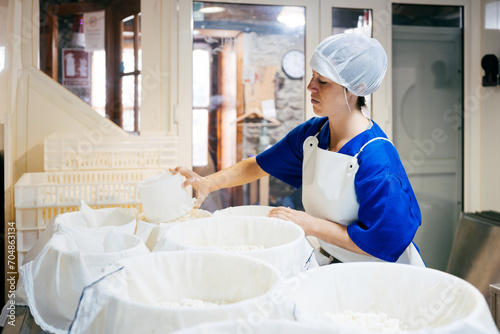 Female worker making cottage cheese at factory