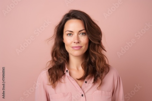 Portrait of a beautiful young woman with long brown hair on pink background © Inigo