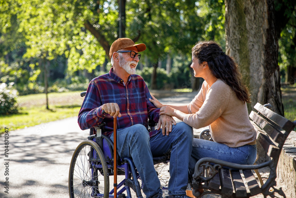 Happy retired senior man in wheelchair talking with volunteer Happy retired senior man in wheelchair talking with volunteer