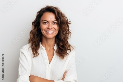 Portrait of a smiling businesswoman standing with arms crossed against white background