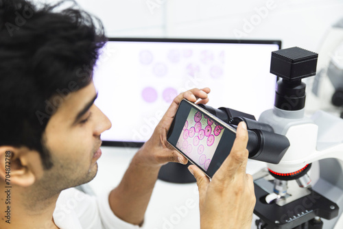 Scientist taking picture of pollen from microscope at laboratory