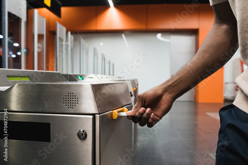 Hand of man inserting metro ticket in electronic barrier photo