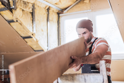 Man measuring wooden plank at home photo