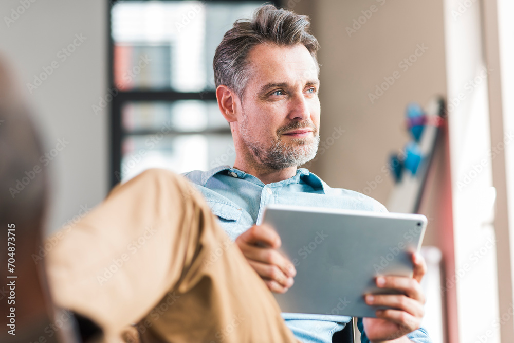 Businessman sitting with tablet PC in hand Businessman sitting with tablet PC in hand