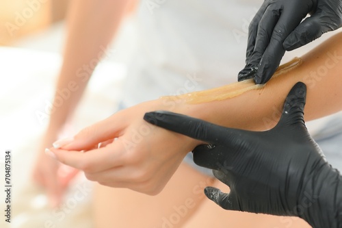 A beautician makes a sugar paste depilation of a woman's hand in a beauty salon photo