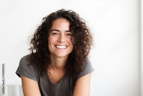 Portrait of a beautiful young woman laughing against a white wall.