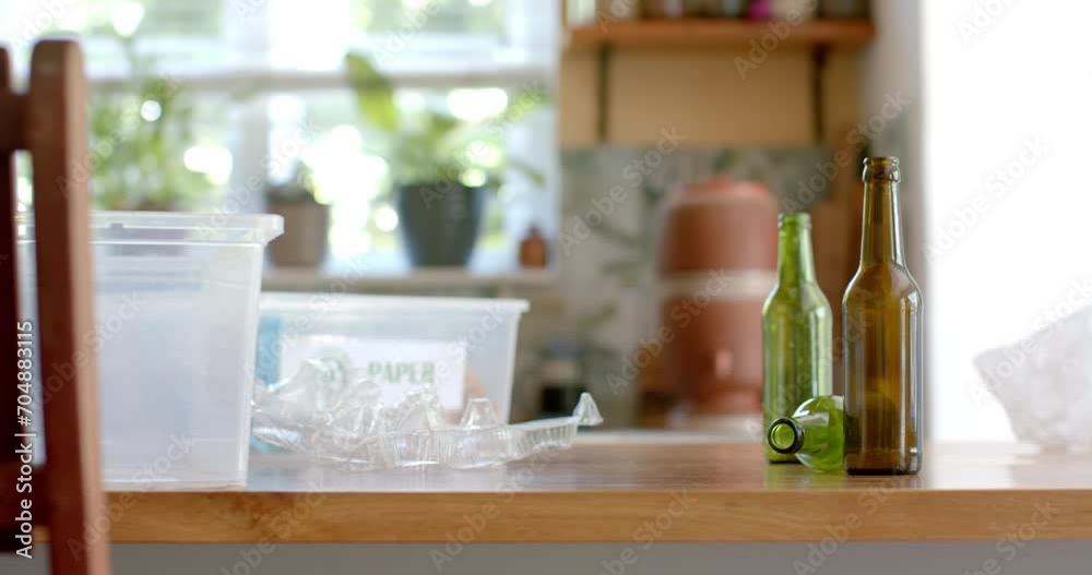 Segregation plastic boxes for waste, plastic and glass bottles on table in kitchen, slow motion Segregation plastic boxes for waste, plastic and glass bottles on table in kitchen, slow motion