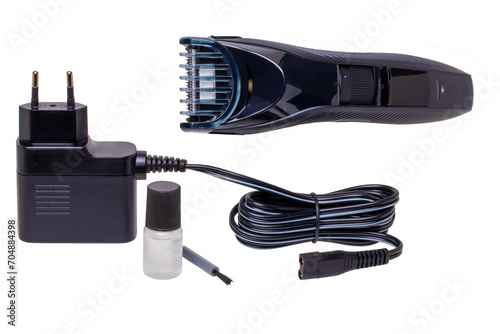 Closeup of a new black and silver rechargeable beard and hair clipper with power supply, brush and oil isolated on white. Cordless hair and beard trimmer. Macro. photo