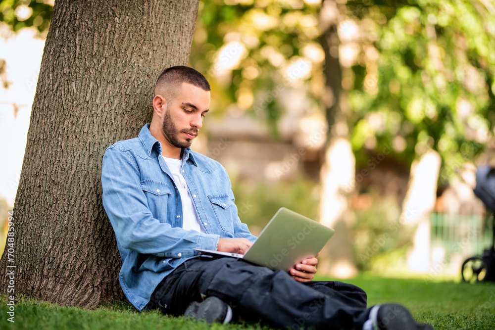 Young man using laptop for studying or working outdoors Young man using laptop for studying or working outdoors