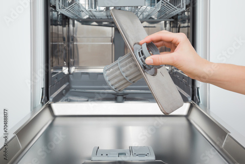 Young adult woman hand holding clean filter for dishwasher. Closeup. Front view. photo