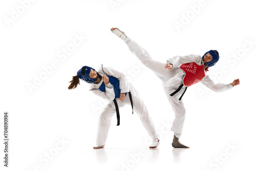 Korean martial art. Asian sport, fighting battle. Two young girl in white dobok, kimono practicing taekwondo isolated over white background. Concept of martial arts, combat sport, competition, action