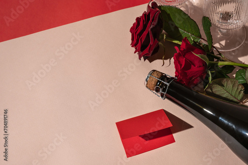 Canvas Print Rose flower bouquet, bottle with sparkling wine, red paper card on peach beige background in bright light with harsh shadows