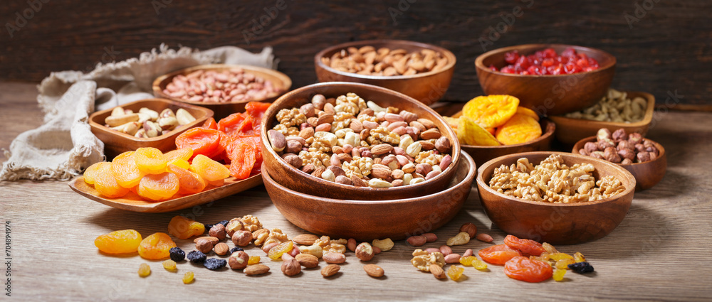 Bowls of mixed nuts and dried fruits on wooden background