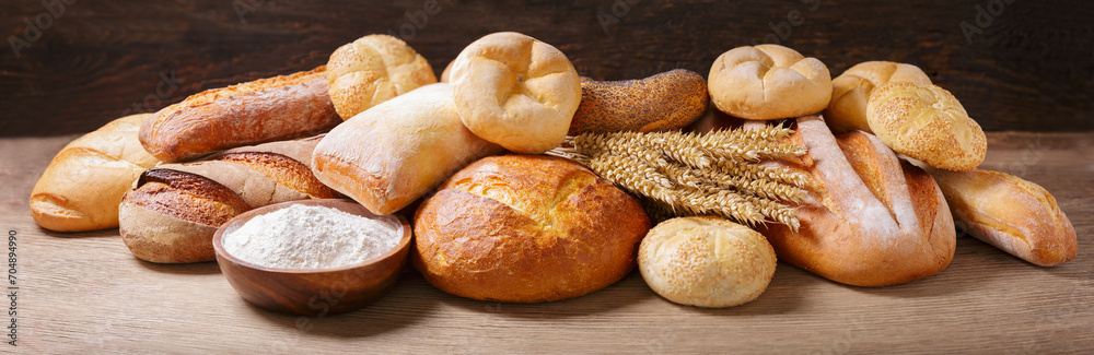 Fresh baked bread, flour and wheat ears on wooden table