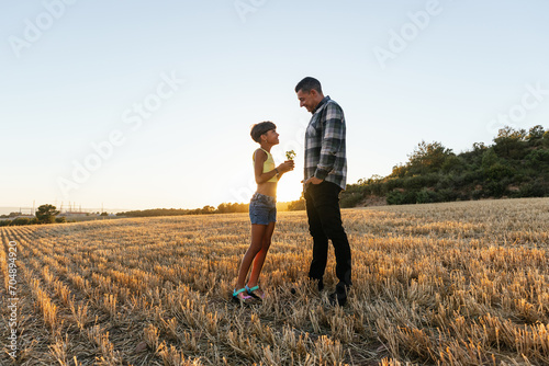 Father and daughter enjoy a sunset outdoors.